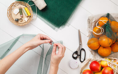 Woman Sews shopping bags instead of plastic bags top view. DIY Reusable mesh shopper. Handmake of Eco bags for shopping in grocery store. Fresh fruits. Eco-friendly shopping. Zero waste. Plastic free
