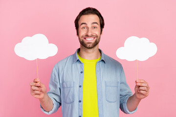 Portrait of smiling good mood man hold two paper cloud on stick weather forecast isolated on pink...