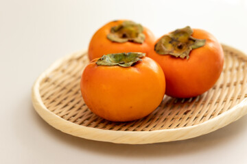 竹ザルの上に三つの柿