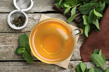 Cup of hot aromatic mint tea on wooden table, flat lay