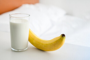 a glass of milk and banana on the table in the bedroom, healthy eating before, sleep concept