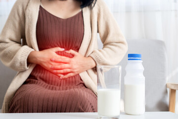 woman holding stomachache after drinking a glass of cow milk feeling bad, discomfort because of...