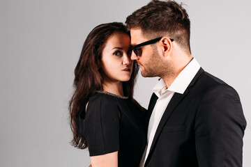 young couple, in black suits with pistols in their hands on a white background in the studio, they depict security guards, bodyguards or agents.
