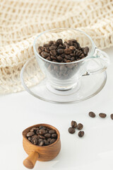 Grains of coffee in a glass cup on a white background.