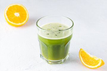 Matcha drink with orange on a light table.