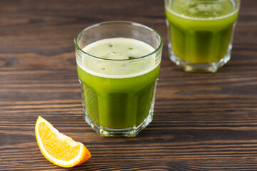 Matcha drink and orange juice in glasses on a wooden table.