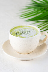 Matcha latte tea with coconut milk on the background of a palm branch.