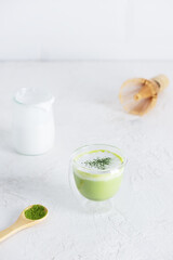 Vegan tea matcha latte with coconut milk in a glass on a light background.