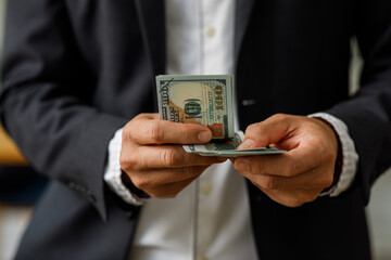 Businessman Hand holding US dollars, American bills money dollars in hand. Saving money and investing or Bribery and corruption concept.