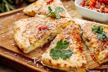 Chicken quesadilla with salsa sauce on wooden serving board