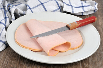 Tranches de jambon blanc dans une assiette avec un couteau posée sur une table