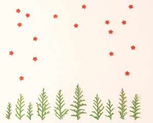 Flat lay winter scene on a beige background. Minimal holiday concept made of green branches and sparkling stars.