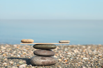 Fototapeta na wymiar Stack of stones with wooden stick on beach, space for text. Harmony and balance concept