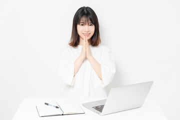 ノートパソコンを使いながら、願い事をする若い女性