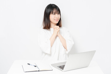 ノートパソコンを使いながら、願い事をする若い女性