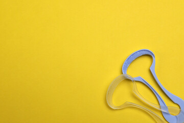 Naklejka premium Tongue cleaners on yellow background, flat lay. Space for text