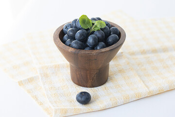 Lot of whole fresh sweet purple blueberry with wooden bowl.