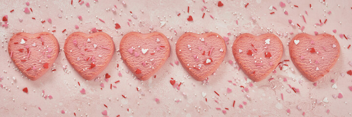 Fototapeta na wymiar Valentine day decorated heart shaped cookies on pink background, top view