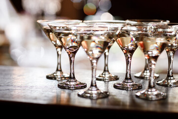 martini glasses in front of gold bokeh background. Luxury cocktail drink in restaurant bar with night lights blur. Classy beverage celebration party for new year, christmas, valentine.
