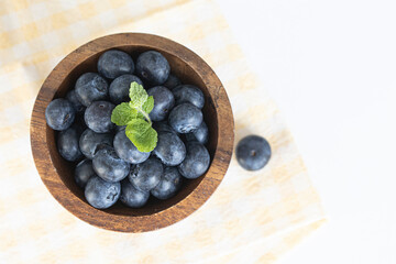 Lot of whole fresh sweet purple blueberry with wooden bowl.