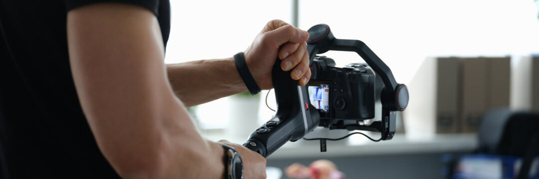 Videographer holds stabilizer with camera in hands closeup