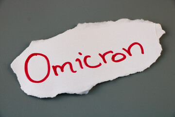 Omicron, text written on piece of torn paper isolated on grey background