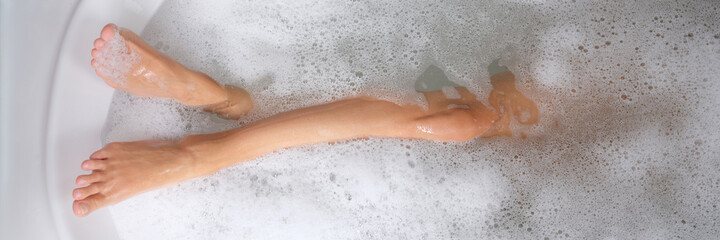 Women beautiful slender legs in bath with water and foam