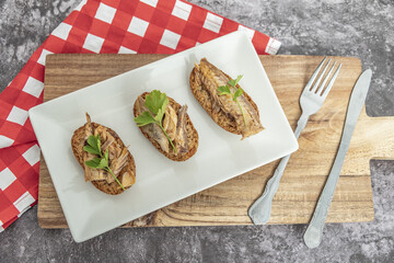 Plate of toasted bread with mackerel in pickled sauce, a typical Spanish tapa.