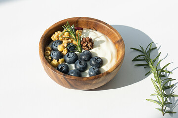Bowl of yogurt with wild berries and fruit on white background.