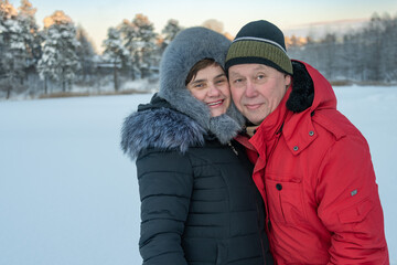 Man and woman smiling on the background of a winter forest lake