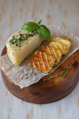 Slices of fried halloumi cheese with a beautiful grilling pattern rests on a wooden tray.