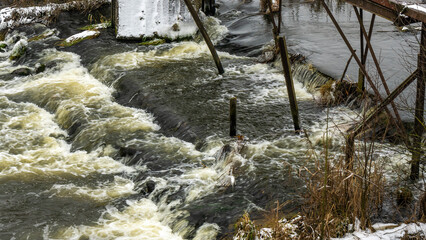 Boiling water in a winter river under a pedestrian bridge. Abstract background. Space for text.