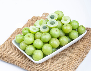 Indian gooseberry fruits or Amla berry ( phyllanthus emblica )  and sliced in white palte on white background.