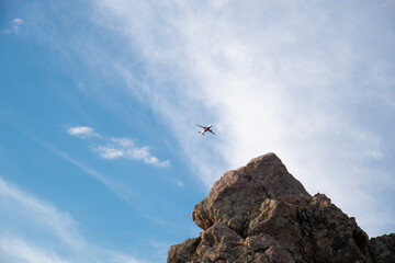 View of a plane flying in the sky over a rock. The concept of flights and tourism - 474893156