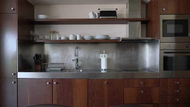 Stand with modern kitchen utensils in inox metal style. The hostel's kitchen is wood paneling.