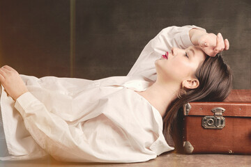Photo of a beautiful girl lying on a suitcase in vintage processing.