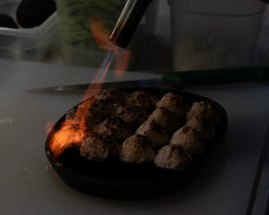 chef with a gas pistol burns a fish dish