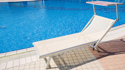 Resort pool. Summer resort chair, relax lounge at luxury hotel pool. Beach lounger chaise. Vacation sunbed. Blue water, sunny happy travel holiday.