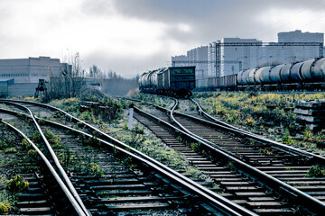 Railroad station with dark sky, mainly cloudy. Abandoned mystical place. Old wagons on tracks