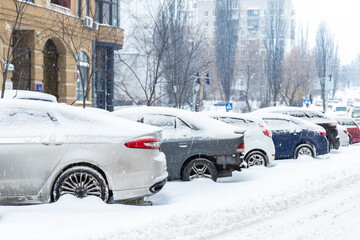 City street driveway parking lot with many cars covered by snow stucked after heavy blizzard snowfall on winter day by dirty snowy pile. Snowdrifts and freezed vehicles. Extreme weather conditions © Kirill Gorlov