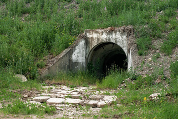 Catacombs tunnel entrance in the mountain. Underground bomb shelter hole. Waste sewage, storm drain