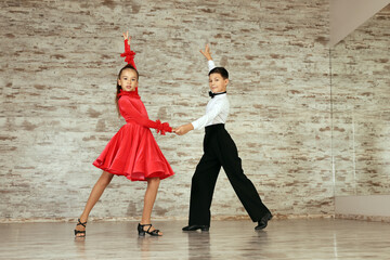 Beautifully dressed couple of kids dancing together in studio