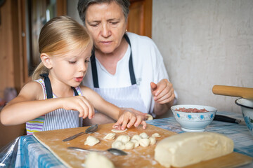 Obraz na płótnie Canvas Girl and grandmother preparing dumplings together