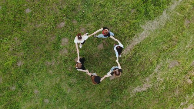 Girls are holding hands spinning in a circle in the summer day.