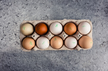 White and brown chicken eggs in a cardboard box on a gray background