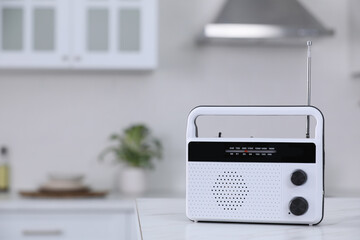 Stylish radio on white marble table in kitchen. Space for text