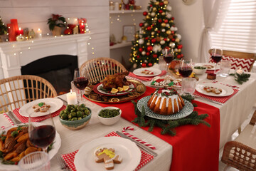 Festive dinner with delicious food and wine on table indoors. Christmas Eve celebration