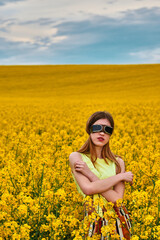 young girl in sunglasses in yellow rapeseed field. portrait
