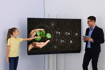Teacher and pupil using interactive board in classroom during lesson