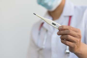 The doctor holds a thermometer that shows abnormally high body temperature and fever.
